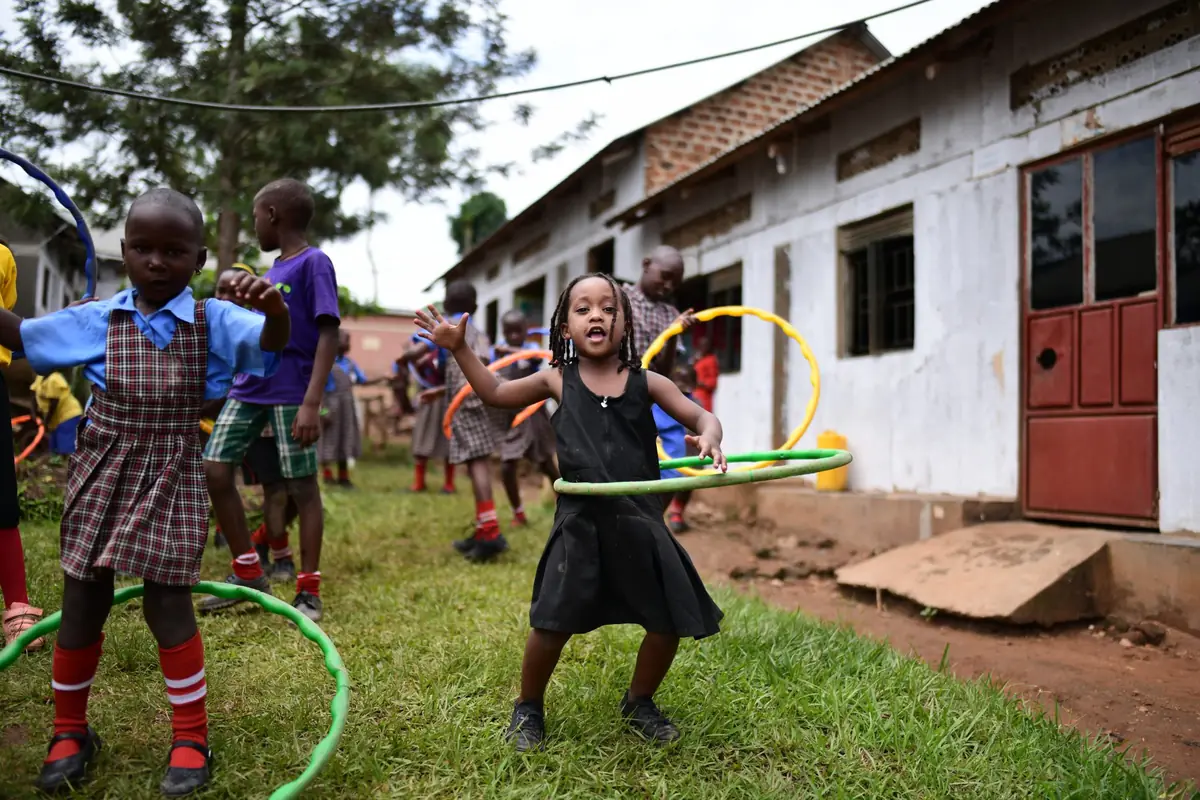 Young children playing with hula hoops outside their school in Uganda