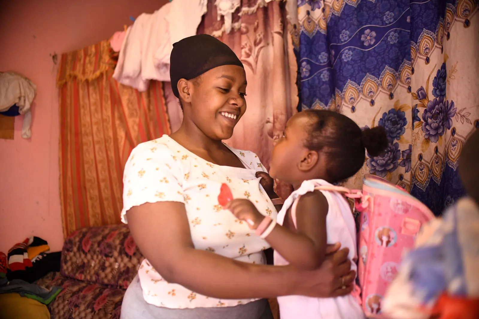 A mother and her young daughter smiling together at home